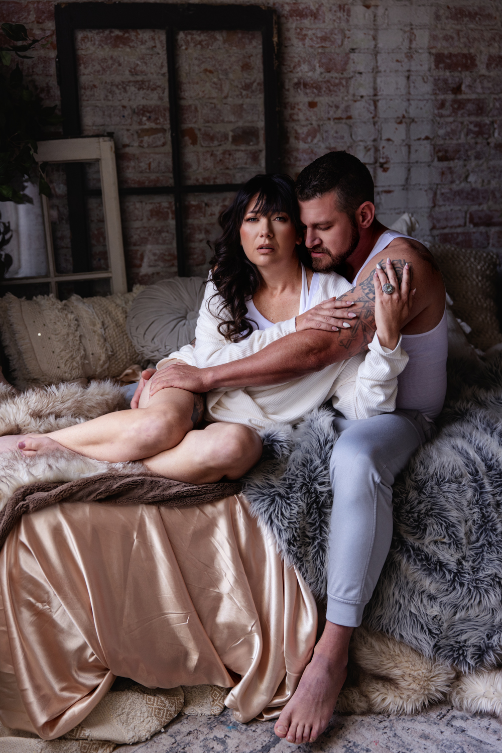 A couple snuggles on the edge of a bed in white after enjoying date night ideas in indianapolis